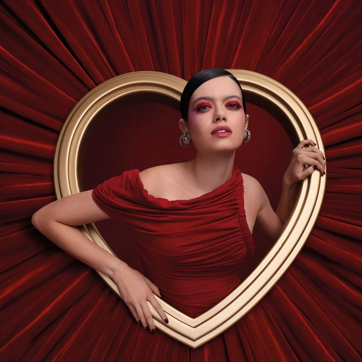 Modelo de vestido vermelho dentro de uma moldura de cora&ccedil;&atilde;o dourada na campanha da cole&ccedil;&atilde;o Alice da Avon