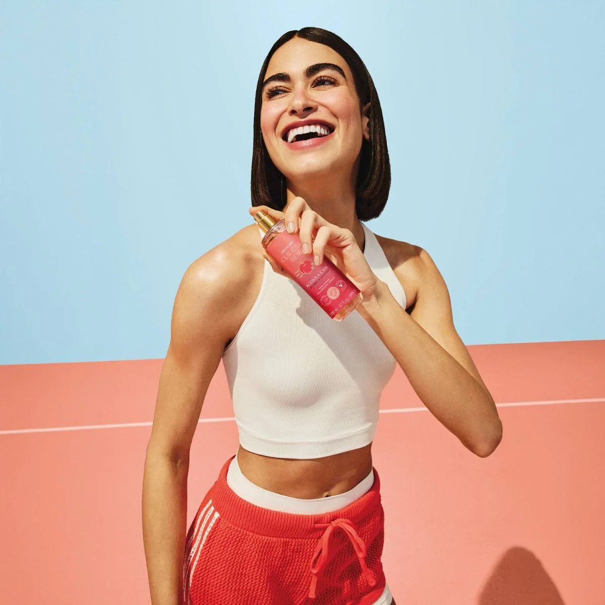 Modelo com roupa de treino segura o body splash Cuide-se Bem Acerola e Vai