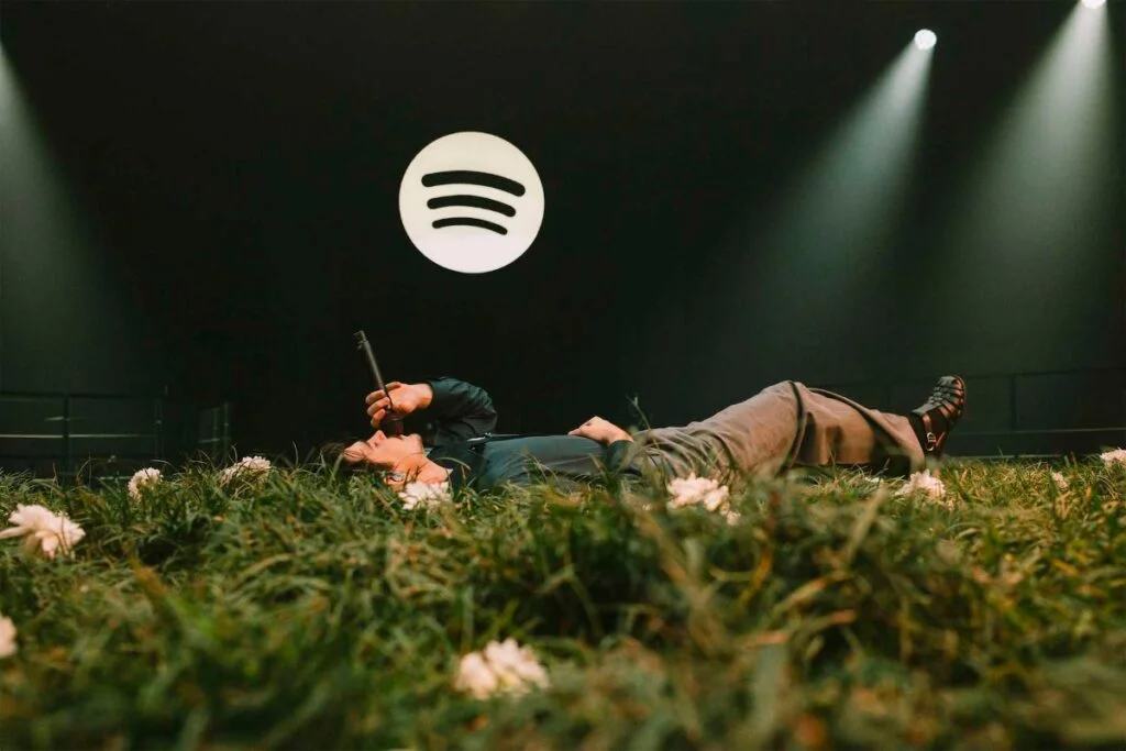 Jão deitado em um palco coberto de grama e flores na performance exclusiva do Spotify