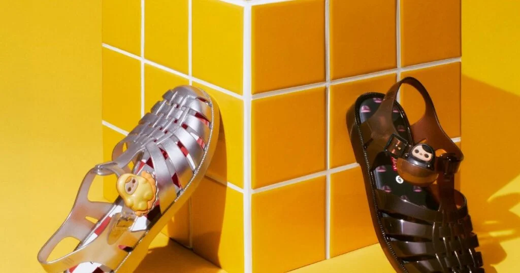 Sandálias Melissa Possession da collab Melissa e POP MART com charms da PUCKY em fundo amarelo