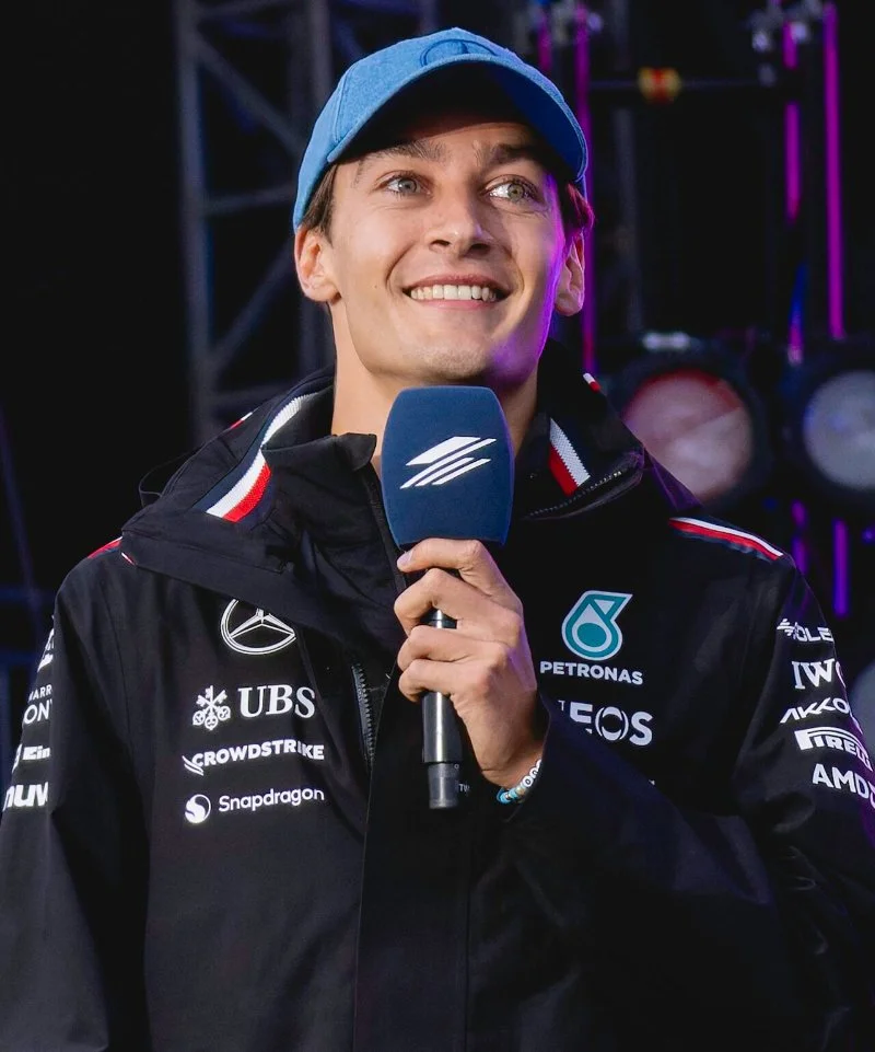 George Russell, piloto da Mercedes, sorrindo com microfone em evento com f&atilde;s