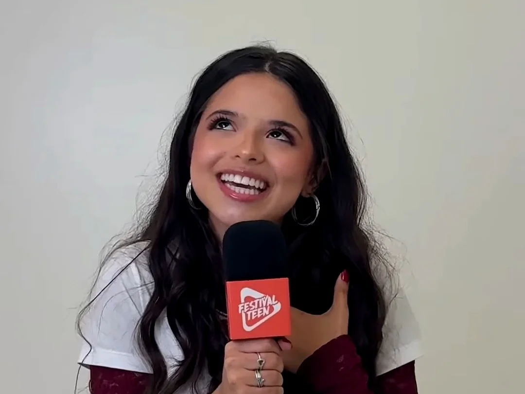 Vivi Lucas gargalha com a mão no peito durante papo com o Festival Teen